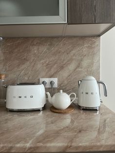 a kitchen counter with three toasters and kettles on it