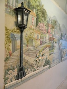 a lamp post in front of a mural on the wall