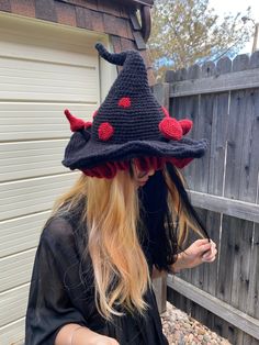 a woman with long blonde hair wearing a knitted hat and looking at her cell phone