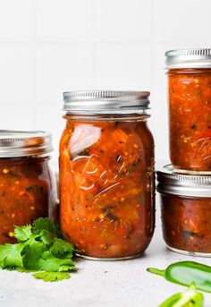 four jars filled with different kinds of food and garnished with cilantro