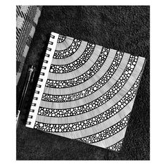 a black and white photo of a spiral notebook with pen on the floor next to it