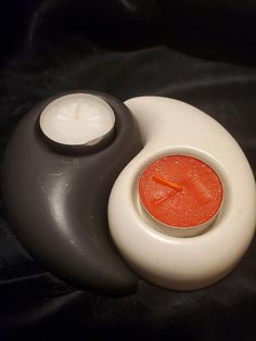 an orange and white candle sitting on top of a black table next to a bowl