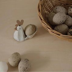 some eggs are in a basket next to two quails and a paper chicken