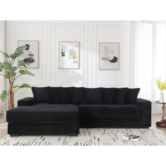 a living room with a large black couch and rugs on the floor in front of white walls