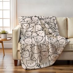 a white couch with a black and white cat blanket on it's back in front of a window