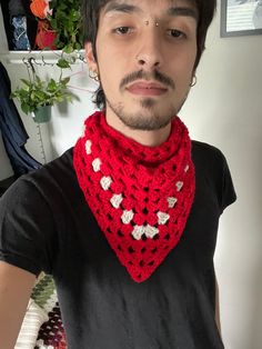 a young man wearing a red crocheted scarf with hearts on the front and neck