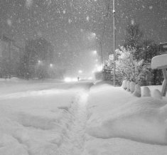 a snow covered street at night with cars driving on it