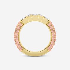 a yellow gold ring with pink and white stones in the center, on a gray background