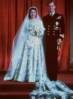 a man and woman standing next to each other in front of red curtained walls