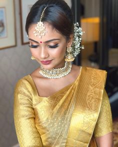 a woman wearing a gold sari with pearls in her hair and jewelry on her head