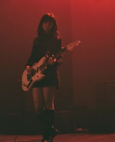 a woman standing on stage with a guitar