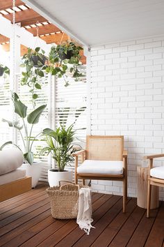 a white brick wall and wooden deck with plants