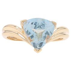 a gold ring with an aqua blue topazte in the center and two leaves on each side