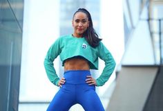 a woman is posing for the camera with her hands on her hips while wearing blue leggings and a green crop top