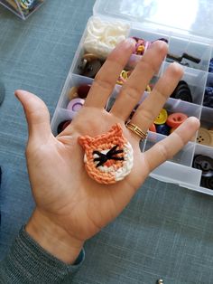 a hand holding an orange and white crocheted ring