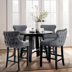 a dining room table with grey chairs and a white vase on top of the table