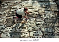 a man standing on top of a pile of old license plates