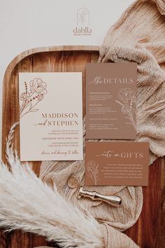 the wedding stationery is laid out on a wooden tray