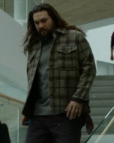 a man with long hair walking down an escalator