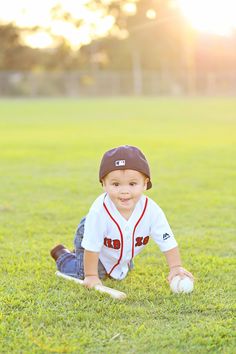 a little boy in a baseball uniform laying on the grass