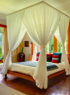 a bed with white drapes on top of it