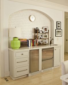 a kitchen with white cabinets and green vase on the counter