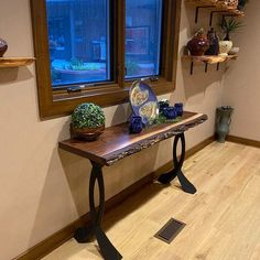 a wooden table sitting in front of a window next to a vase and potted plant