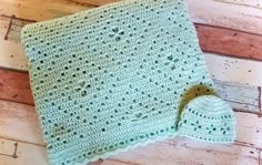 a green crocheted blanket laying on top of a wooden floor