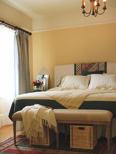 a bedroom with a large bed and two baskets under the foot board on the floor