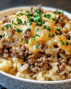 a close up of a bowl of food with meat and cheese on top, sitting on a table