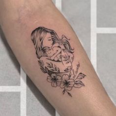 a woman's arm with a tattoo on it and flowers around the arm area