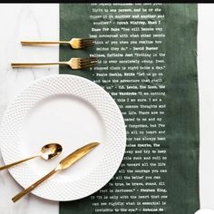 a white plate topped with gold utensils next to a green napkin