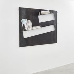 a metal book shelf mounted to the side of a wall next to a white wall