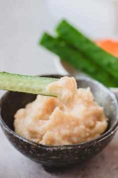 a small bowl filled with mashed potatoes and cucumbers next to carrots