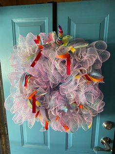 a pink mesh wreath hanging on a blue door with a birthday cake in the center