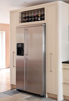 a stainless steel refrigerator with wine bottles on the top and bottom shelves in a kitchen