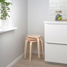 two stools in the corner of a white room