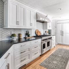 a large kitchen with white cabinets and black counter tops is pictured in this image from the front view