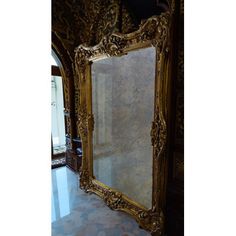 an ornate gold framed mirror sitting on top of a tiled floor next to a wall