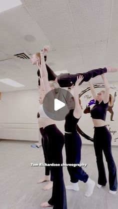 three women in black and white outfits are doing tricks on the dance floor with their hands up