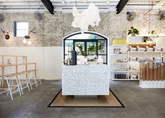 the interior of a store with white furniture and brick walls, windows, and shelves