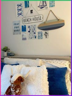 a stuffed animal laying on top of a bed next to a wall mounted with pictures