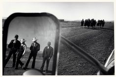 a group of men standing on top of a dirt road next to a horse drawn carriage