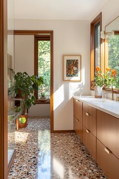 a bathroom with wood cabinets and marble counter tops, along with a large window that opens to the outdoors