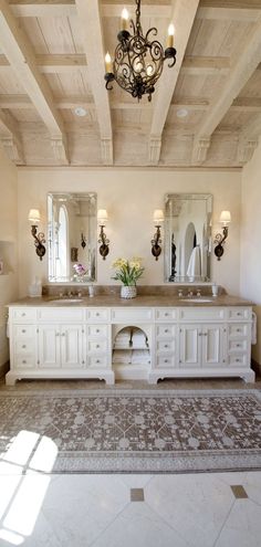 a large bathroom with double sinks and two mirrors on the wall, along with a chandelier