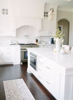 a kitchen with white cabinets and an island that has a potted plant on it