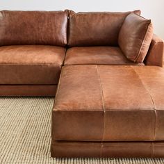 a large brown leather couch sitting on top of a rug