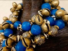 This bold, chunky and dramatic triple strand beaded necklace is heavy, so please know your tolerance before you purchase. If you are a serious buyer, I would be open to removing one of the strands to make this lighter. The components include beautiful blue African recycled glass beads, zebu bone rondelles, ornate vintage metal beads, Asian brass chimes, brass rings, faceted blue crystals and shiny gold balls. Adjusts from 18-22" with gold tone hardware, an xl fancy lobster claw clasp and a 4" ex Unique Blue Wooden Beads, Blue Wooden Beads, Artisan Blue Beaded Necklaces, Blue Jewelry With Wooden Beads, Unique Blue Jewelry With Wooden Beads, Unique Blue Wooden Beaded Necklaces, Unique Blue Beaded Bracelets With Polished Beads, Brass Rings, Recycled Glass Bead