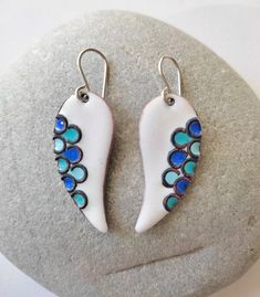 These earrings have the design of bird wings. Minimalist in style but they have a meticulous work. Earrings with a white background and blue scales, made by hand in enameled copper applying the cloissoné technique, which consists of the integration of metallic threads in the enamel, to create divisions in which enamel is applied. They can also be made in other colors. Light and comfortable to wear earrings. White Wing-shaped Earrings For Gift, White Hand Painted Drop Earrings, Unique White Enamel Earrings, Blue Wing-shaped Jewelry Gift, Unique White Enamel Jewelry, Handmade White Enamel Earrings, Handmade White Enamel Jewelry, White Enamel Drop Earrings, Hand Painted Blue Enamel Earrings