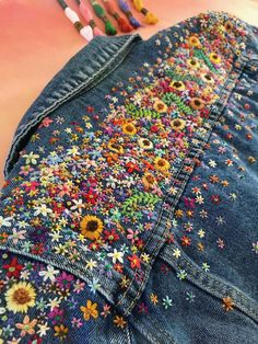 a pair of jean shorts with flowers on them and crayons in the background